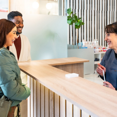 Dental receptionist smiling at couple in lobby