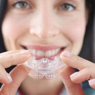Smiling woman holding mouthguard
