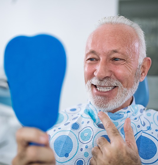 a man looking at his smile in a small mirror