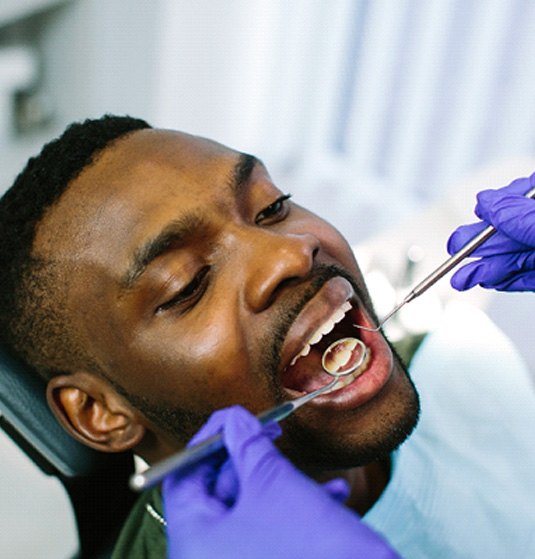 Dentist examining patient's teeth with dental mirror