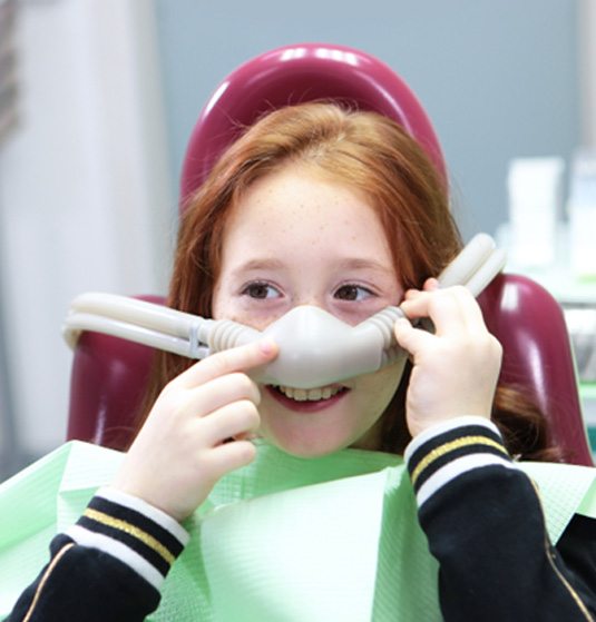 Smiling child holding nitrous oxide mask