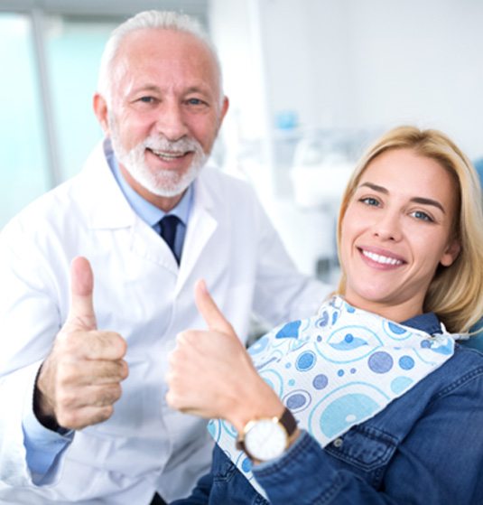 Smiling dentist and patient giving thumbs up