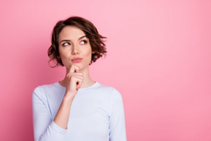 Woman pressing a finger to her chin in a questioning pose