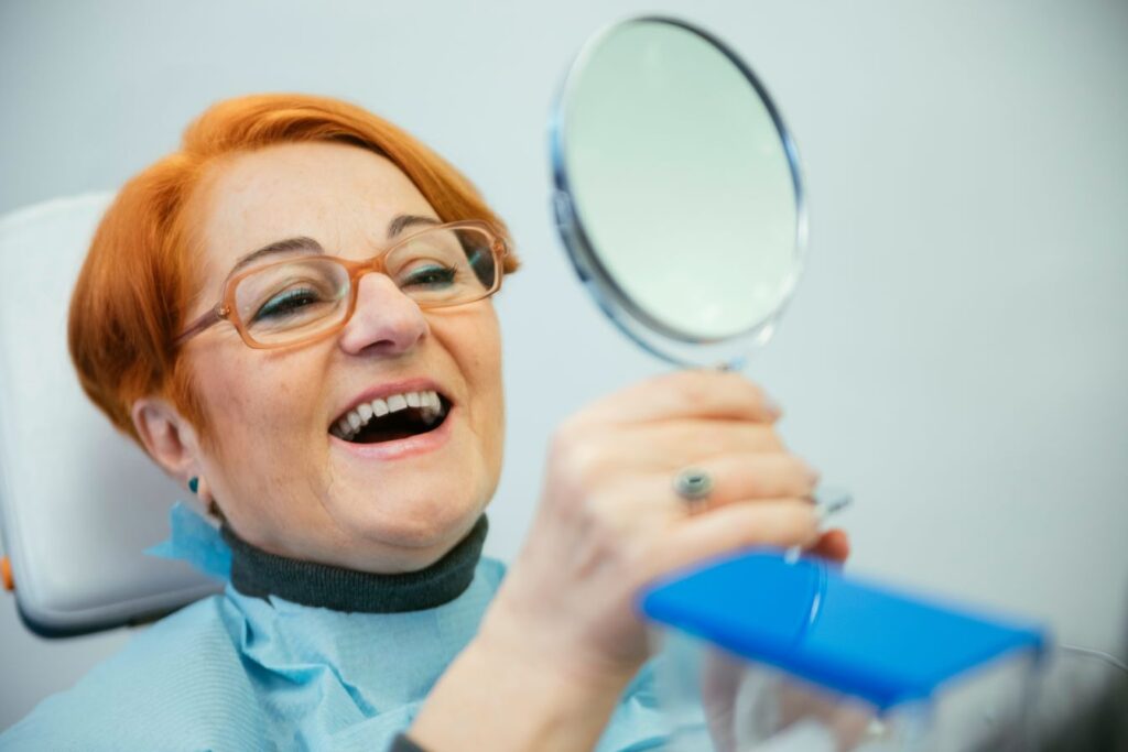 A woman wearing a new pair of dentures for the first time.